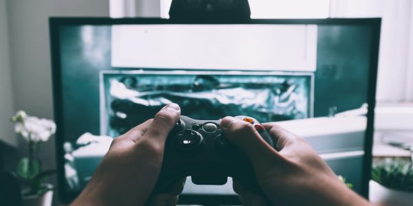 person holding game controller in-front of television