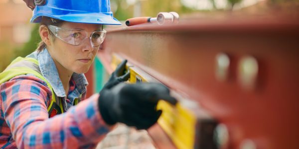 a young female steel erector marks off steel where she is about to drill