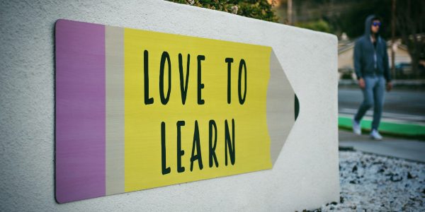 love to learn pencil signage on wall near walking man